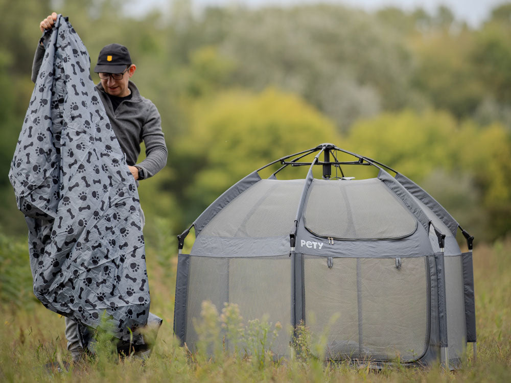 Ein Mann steht mit der Abdeckung Plus neben dem PETY Hundelaufstall